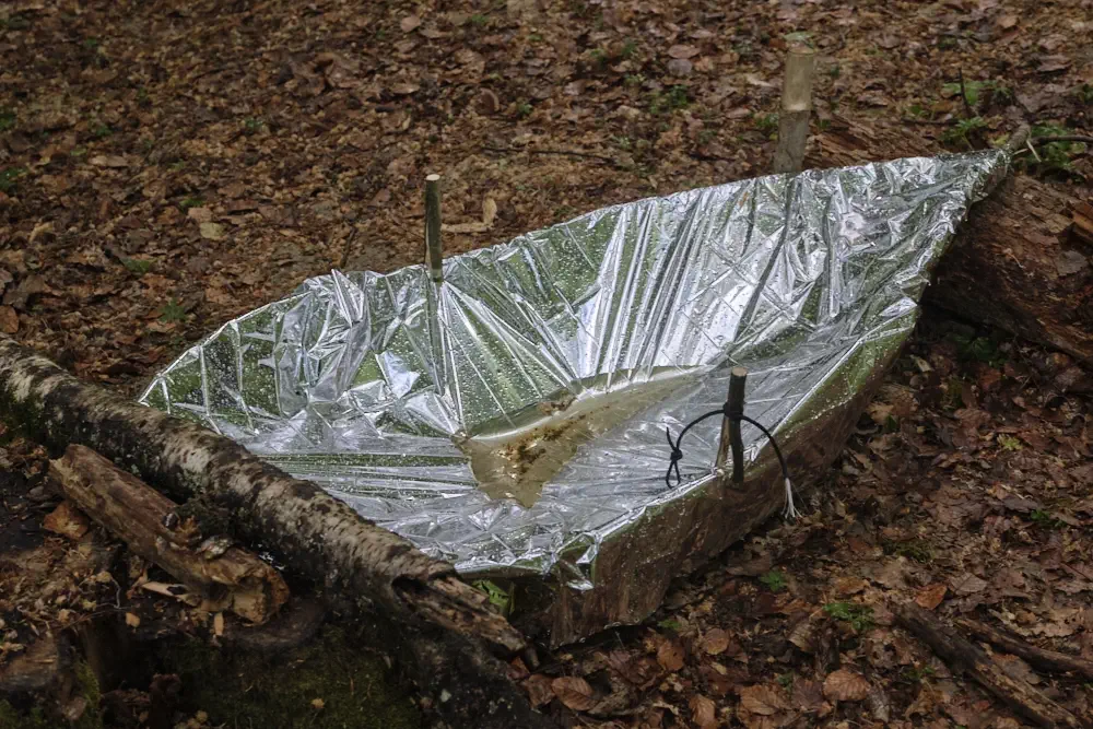 Wasser auffangen mit einer Rettungsdecke beim Survival